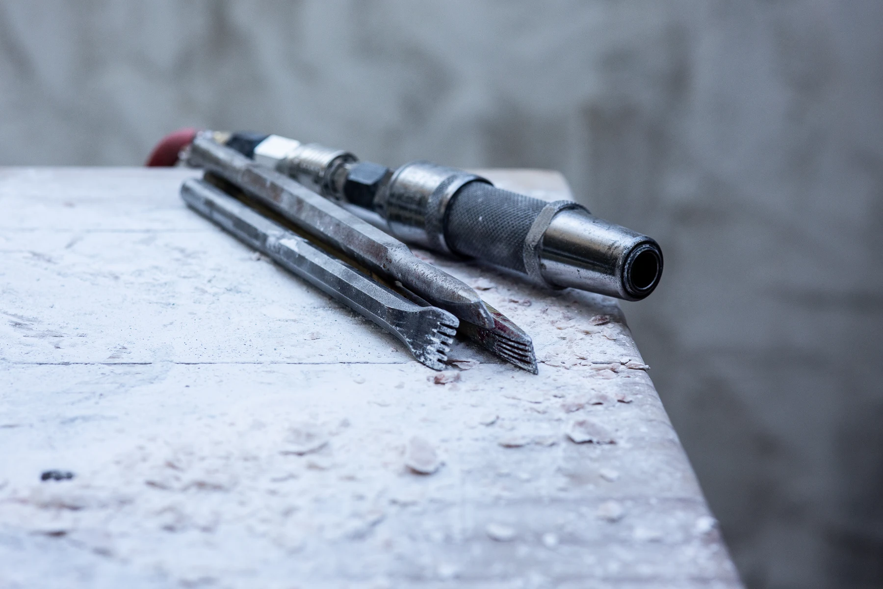 Close-up of old carving tools and chisels resting on a dusty worktable in a stone carving studio